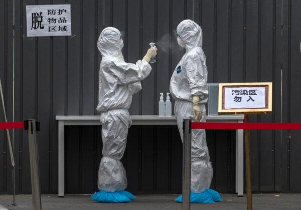 Chinese epidemic control workers wear protective suits as they disinfect each other after performing nucleic acid swab test for COVID-19 on citizens at a government testing site in Xicheng District during an organized tour on June 24, 2020 in Beijing. (Kevin Frayer/Getty Images)