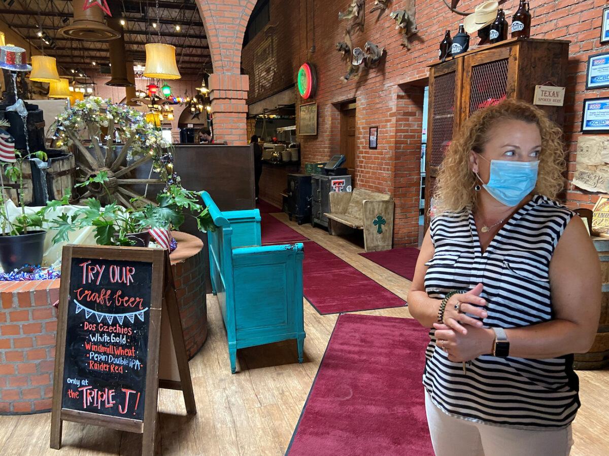 An owner of a restaurant looks out the establishment's front door, in Lubbock, Texas, June 26, 2020. (Reuters/Brad Brooks)