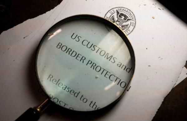 A magnifying glass is seen next to a logo of the Customs and Border Protection, Trade and Cargo Division at John F. Kennedy Airport’s U.S. Postal Service facility in New York on June 24, 2019. (Johannes Eisele/AFP via Getty Images)