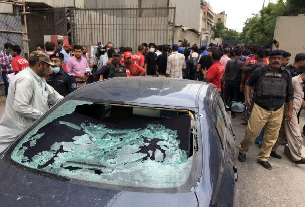A plainclothes police officer (L) surveys the site of an attack at the Pakistan Stocks Exchange entrance in Karachi on June 29, 2020. (Akhtar Soomro/Reuters)