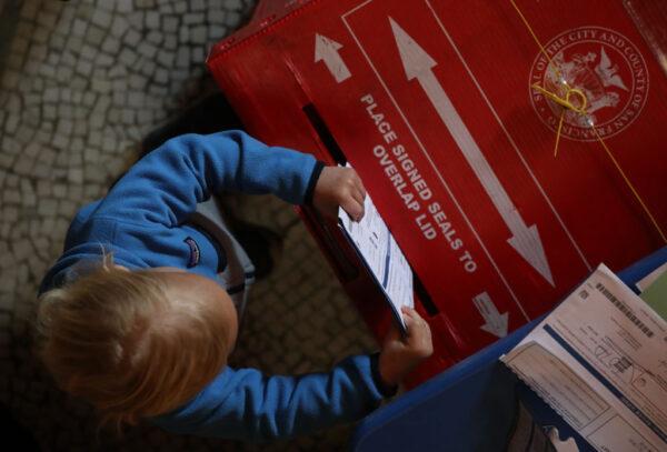 A young boy puts filled-out ballots into a box in a polling station at the San Francisco Columbarium & Funeral Home in San Francisco on March 3, 2020. (Justin Sullivan/Getty Images)