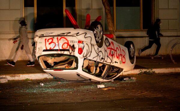 A vandalized car is flipped upside down as protesters face off against police in Oakland, Calif., on May 29, 2020. (Josh Edelson/AFP via Getty Images)