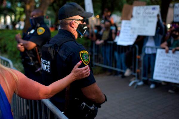 A woman puts her hand on a police officer standing between attendees of a Police Appreciation rally and counter-protesters at City Hall in Houston, on June 18, 2020. (Mark Felix/AFP via Getty Images)