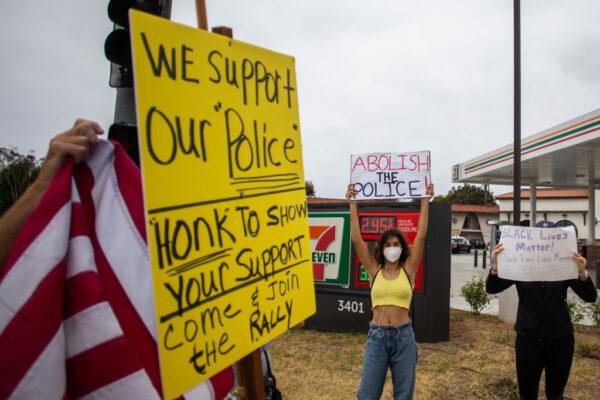 A woman holds a sign that says “Abolish the police,” across from a pro-police demonstration in Torrance, Calif., on June 20, 2020. (Apu Gomes/AFP via Getty Images)
