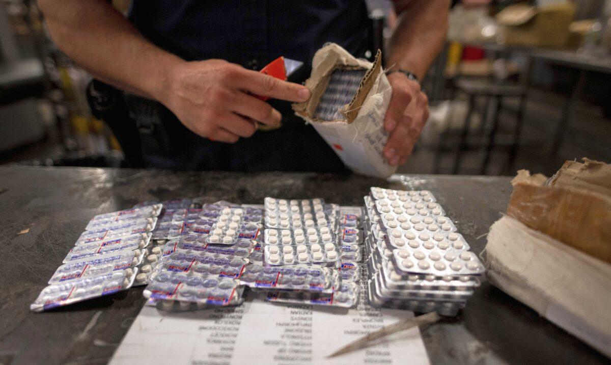 An officer from the U.S. Customs and Border Protection, Trade, and Cargo Division finds oxycodone pills in a parcel at John F. Kennedy Airport's U.S. Postal Service facility in New York on June 24, 2019. (Johannes Eisele/AFP via Getty Images)