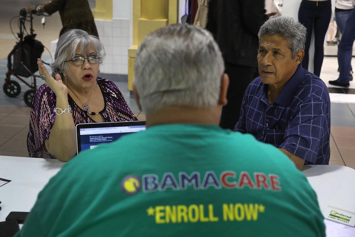 Isabel Diaz Tinoco (L) and Jose Luis Tinoco speak with Otto Hernandez, an insurance agent from Sunshine Life and Health Advisors, as they shop for insurance under the Affordable Care Act at a store setup in the Mall of Americas in Miami, on Nov. 1, 2017. (Joe Raedle/Getty Images)