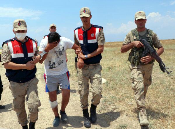 Paramilitary police detain a suspected man in Lake Van, in eastern Turkey, on July 1, 2020. Up to 60 migrants may have been trapped in a boat that sank in the lake last week, Turkey’s Interior Minister Suleyman Soylu said Wednesday. (DHA via AP)