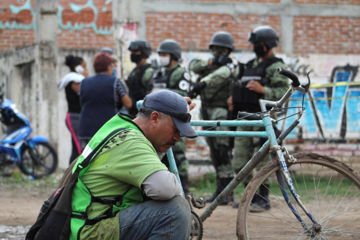 A man sits as soldiers keep watch outside a drug rehabilitation facility where assailants killed at least 24 people, according to Guanajuato state police, in Irapuato, Mexico, on July 1, 2020. (Karla Ramos/Reuters)