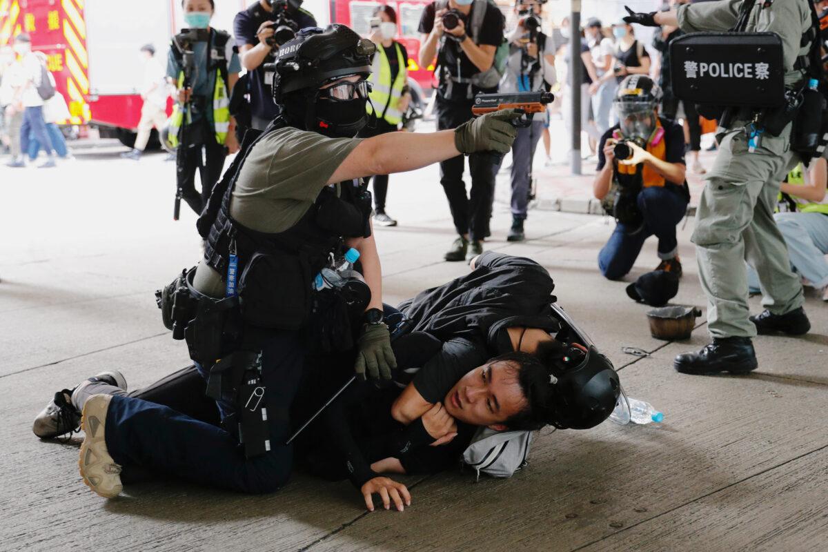 A police officer raises his pepper spray handgun as he detains a man during a march against the national security law in Hong Kong, on July 1, 2020. (Tyrone Siu/Reuters)