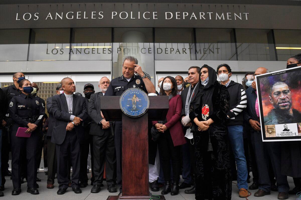 Los Angeles Police Chief Michel Moore speaks as someone holds up a portrait of George Floyd during a vigil with members of professional associations and the interfaith community at Los Angeles Police Department headquarters, on June 5, 2020, (Mark J. Terrill/AP Photo)