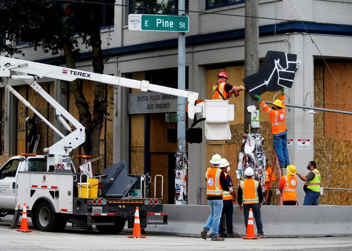 Seattle Department of Transportation workers remove a large Black Power fist sign in front of the Seattle Police Department's East Precinct as police retake the Capitol Hill Occupied Protest (CHOP) area in Seattle on July 1, 2020. (Lindsey Wasson/Reuters)