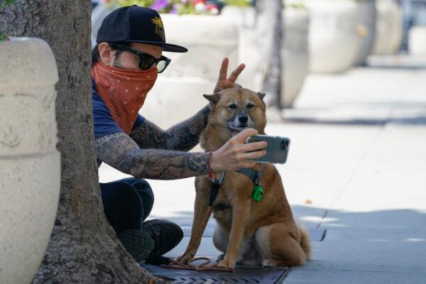Andrew Stuart wears a bandana as a mask while taking a selfie with his dog, Voltron, on Sunset Blvd, in West Hollywood, Calif., on July 2, 2020. (Ashley Landis/AP Photo)