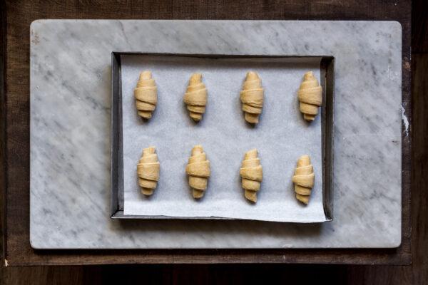 Roll up each triangle from base to tip and arrange on a baking sheet to rise. (Photo by Giulia Scarpaleggia)