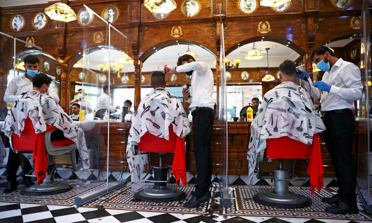 Men have their hair cut at Savvas Barbers as it reopened following the outbreak of the coronavirus disease (COVID-19), in London, UK, on July 4, 2020. (Hannah McKay/Reuters)
