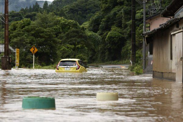 A car is stuck in a flooded road by heavy rain in Yatsushiro, Kumamoto prefecture, southwestern Japan on July 4, 2020. (Kyodo News via AP)