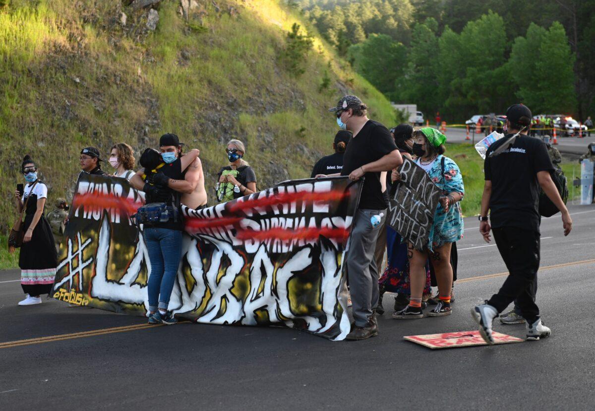 Protesters hug shortly before being arrested for blocking the road to Mount Rushmore National Monument in Keystone, S.D., on July 3, 2020. (Andrew Caballero-Reynolds/AFP via Getty Images)