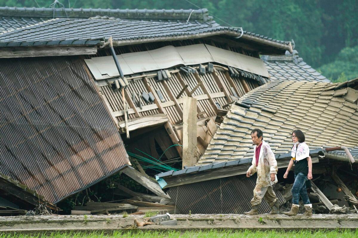 A couple walks in front of houses damaged by flooding in Kuma village, Kumamoto prefecture, southwestern Japan, on July 5, 2020. (Koji Harada/Kyodo News via AP)