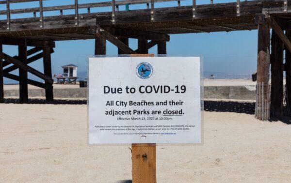 A beach closure sign sits in the sand at the Seal Beach Pier in Seal Beach, Calif., on July 4, 2020. (John Fredricks/The Epoch Times)