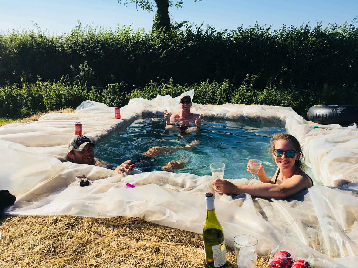 Ed (middle), Ed's wife, Jessica (right), and friend Jon (left) relaxing in their hay bale pool on a local dairy farm in Hazelbury Bryan (Caters News)