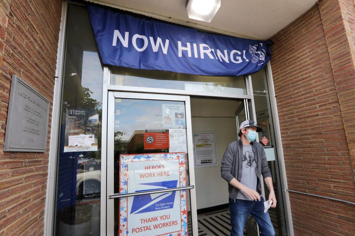 A customer walks out of a U.S. Post Office branch and under a banner advertising a job opening, in Seattle, on June 4, 2020. (Elaine Thompson/File/AP Photo/)