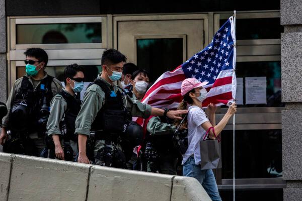 Police remove a woman holding a US flag from outside the US consulate during a march to celebrate US Independence Day in Hong Kong on July 4, 2020. (Isaac Lawrence/AFP via Getty Images)