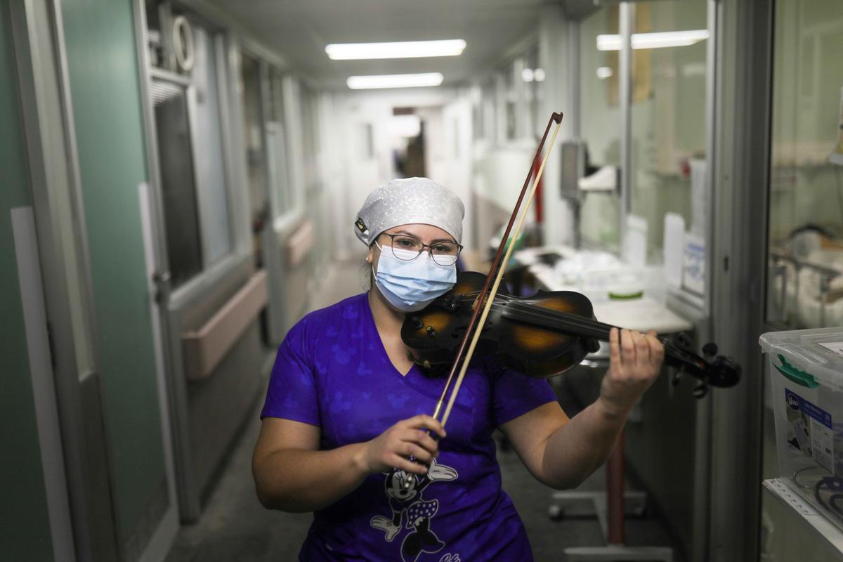 Chilean nurse Damaris Silva plays the violin for patients suffering from the virus in the intensive care unit of the El Pino de San Bernardo hospital, in Santiago, Chile, July 2, 2020. (Pablo Sanhueza/REUTERS)