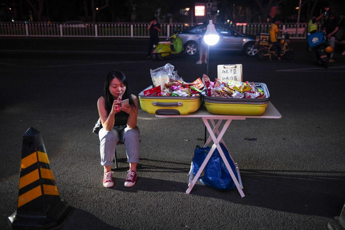 A street vendor waits for customers on the roadside outside a shopping mall in Beijing, China on June 10, 2020. (Greg Baker/AFP via Getty Images)