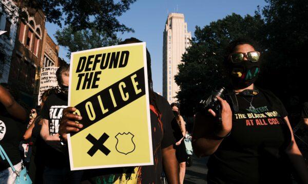 A protester carries a sign that reads "Defund The Police" during the Black Women Matter "Say Her Name" march in Richmond, Va., on July 3, 2020. (Eze Amos/Getty Images)