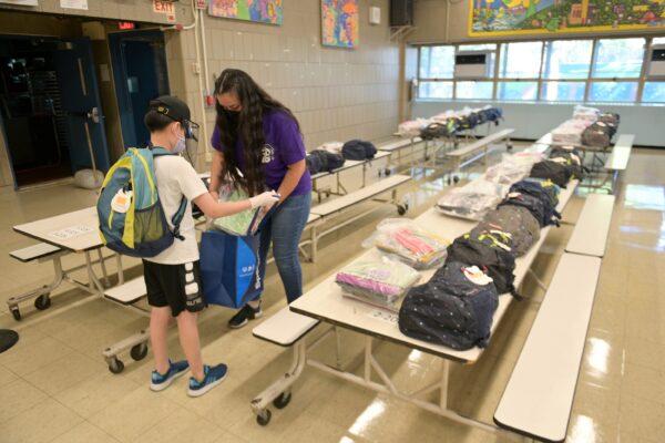 Schoolteacher Aurora Chen hands belongings left behind before schools were shut down to a student who just graduated at Yung Wing School P.S. 124 in New York City on June 29, 2020. (Michael Loccisano/Getty Images)