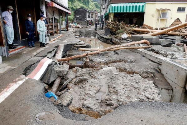 People stand near a road damaged by a heavy rain in Hita, Oita prefecture, southern Japan on July 9, 2020. (Kyodo News via AP)