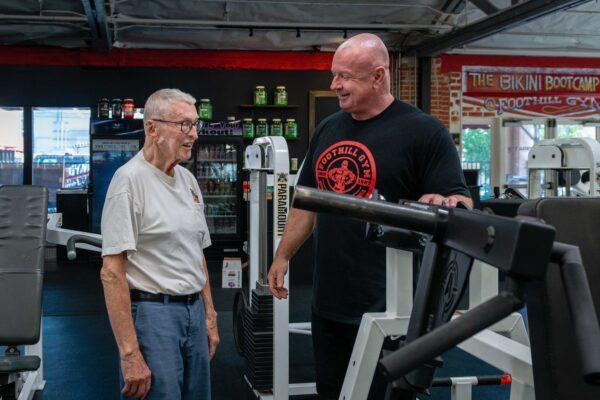  Art Ballard takes a break between sets to chat with Foothill Gym owner Brian Whelan on June 13. (Heidi de Marco, KHN)