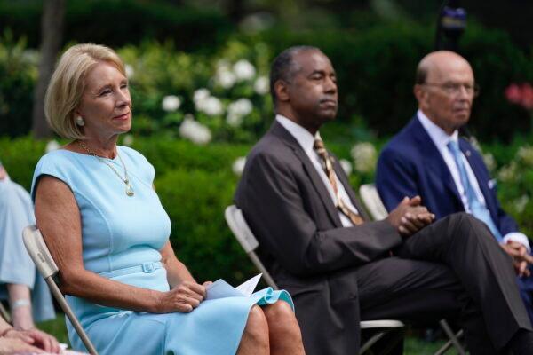 From left, Education Secretary Betsy DeVos, Housing and Urban Development Secretary Ben Carson and Commerce Secretary Wilbur Ross listen as President Donald Trump speaks before signing an executive order on the "White House Hispanic Prosperity Initiative" in the Rose Garden of the White House, in Washington, on July 9, 2020. (AP Photo/Evan Vucci)