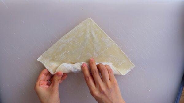 Fold the bottom corner up and over the filling, then tightly roll it up halfway. (Photo by CiCi Li)