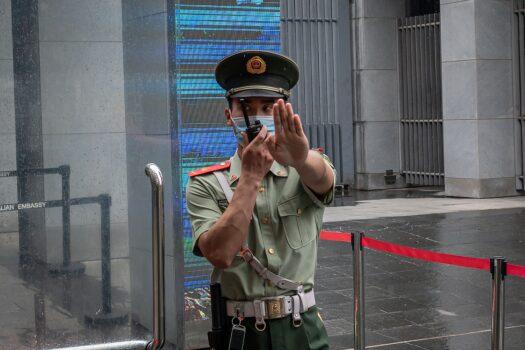 A Chinese paramilitary police officer gestures and speaks over his two-way radio while standing at the entrance gate of the Australian embassy in Beijing on July 9, 2020. (Nicolas Asfour/AFP via Getty Images)
