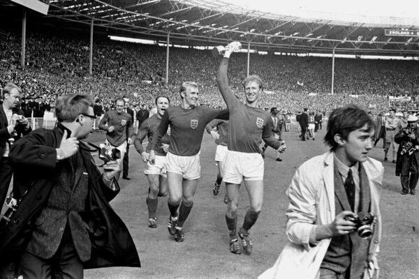 England's Jack Charlton,(R), holds the Jules Rimet trophy aloft as he parades it around Wembley with teammate Bobby Moore following their 4-2 win over West Germany, on July 30, 1966.  (PA via AP)