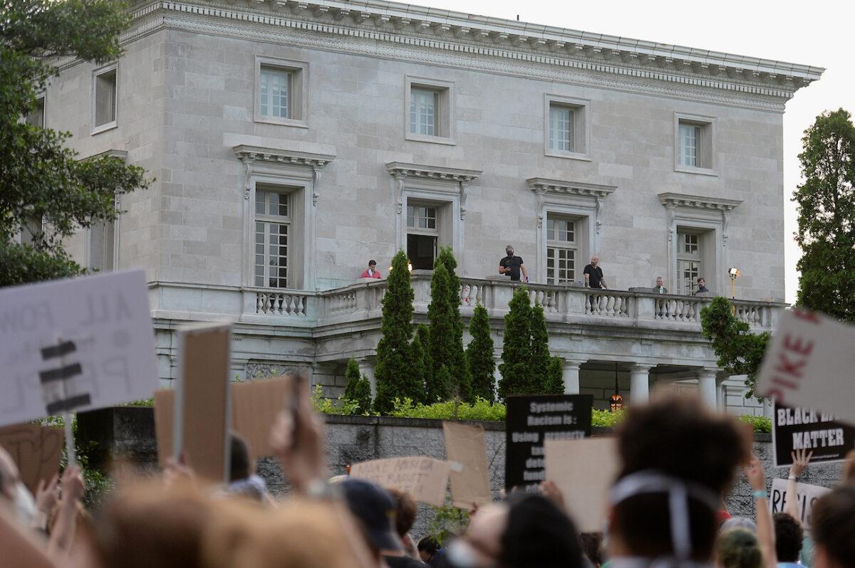 Security personnel stand on the balcony the home of Mark and Patricia McCloskey as protesters gather outside their neighborhood in St. Louis, Mo., on July 3, 2020. (Michael B. Thomas/Getty Images)