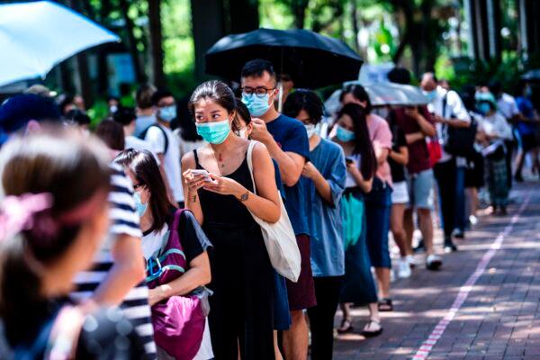 A woman (centre L) uses her phone while waiting to vote during primary elections in Hong Kong on July 12, 2020. (Isaac Lawrence/AFP via Getty Images)