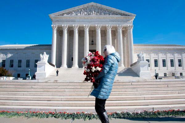 A woman helps lay 3,000 carnations to represent the approximately 3,000 abortions that occur in the United States every day, on the 46th anniversary of the Roe v Wade decision, in front of the U.S. Supreme Court in Washington on Jan. 22, 2019. (Jim Watson/AFP via Getty Images)