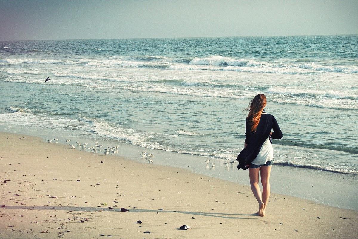 A woman walking on the beach. (Free Photos/Pixabay)