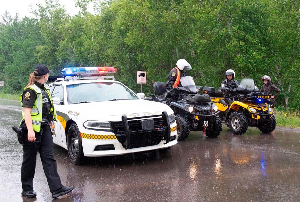 Surete du Quebec officers block the road accessing a search area near Saint-Apollinaire, Que. on July 11, 2020. (Jacques Boissinot/The Canadian Press)