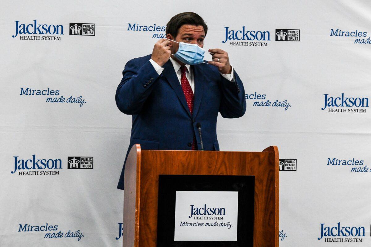 Florida Gov. Ron DeSantis puts on a mask during a press conference at Jackson Memorial Hospital in Miami, Fla., on July 13, 2020. (Chandan Khanna/AFP via Getty Images)