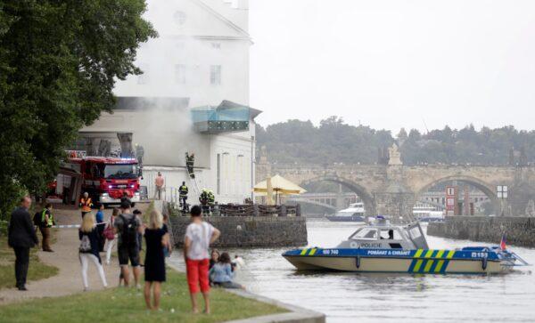 People watch as smoke rises from a technical building of the Kampa Museum in Prague, Czech Republic, on July 15, 2020. (Petr David Josek/AP Photo)