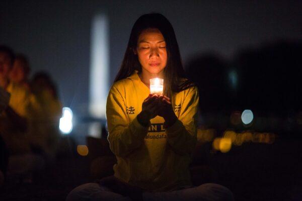 A woman joins Falun Gong practitioners hold a candlelight vigil at the Lincoln Memorial in Washington on July 20, 2017. (Benjamin Chasteen/The Epoch Times)