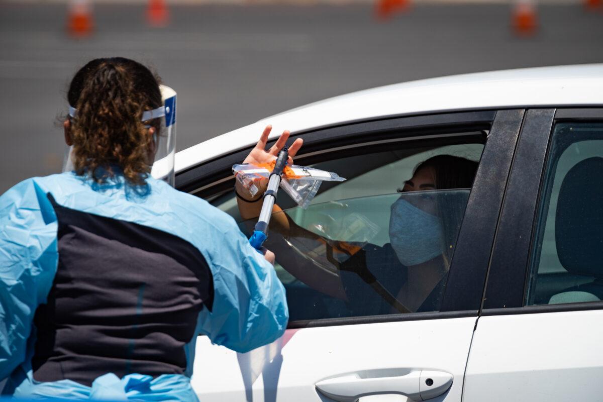 A patient hands over her swab test for COVID-19 at a new, large-scale testing site at the Anaheim Convention Center, in Anaheim, Calif., on July 15, 2020. (John Fredricks/The Epoch Times)