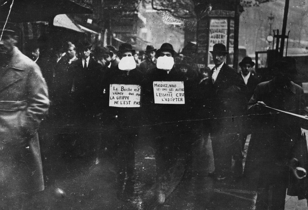 Two men wearing and advocating the use of flu masks in Paris during the 1918 flu epidemic which followed World War I, on March 1, 1919. (Topical Press Agency/Getty Images)