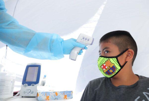 A boy has his temperature checked as he receives a free COVID-19 test at a St. John's Well Child and Family Center mobile clinic set up outside Walker Temple AME Church in South Los Angeles in Los Angeles, California, on July 15, 2020. (Mario Tama/Getty Images)