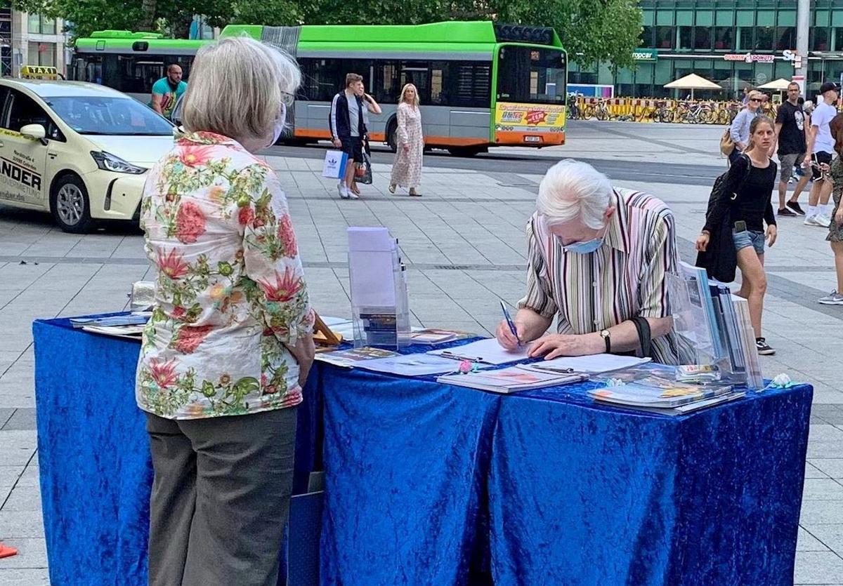 An elderly man signs petition to stop the persecution of Falun Gong in China in Hannover, Germany, on June 13, 2020. (<a href="https://en.minghui.org/html/articles/2020/6/22/185613.html">Minghui</a>)