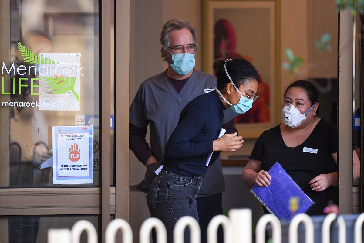 People wearing face masks are seen at the entrance of the Menarock Life aged care facility, where a cluster of some 28 new infections had been reported, in the Melbourne suburb of Essendon on July 14, 2020. (William West/AFP via Getty Images)