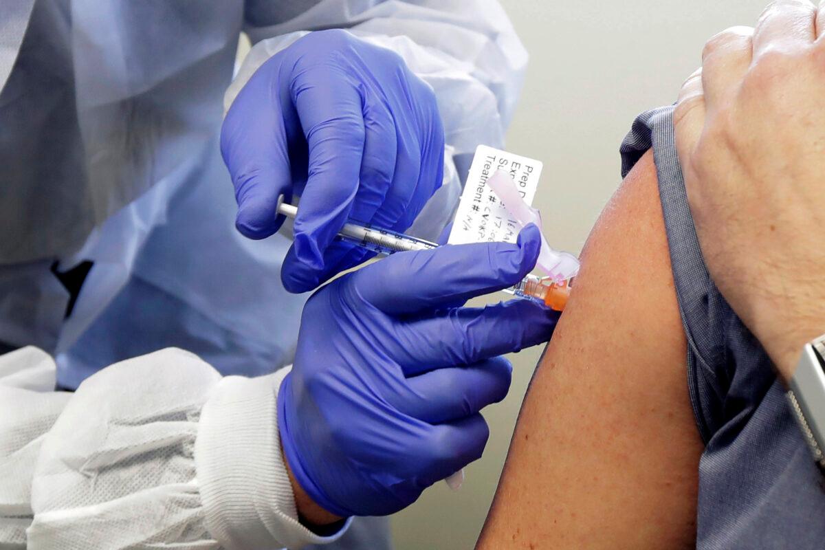 A subject receives a shot in the first-stage safety study clinical trial of a potential vaccine by Moderna for COVID-19 at the Kaiser Permanente Washington Health Research Institute in Seattle, Wash., on March 16, 2020. (Ted S. Warren/AP Photo)