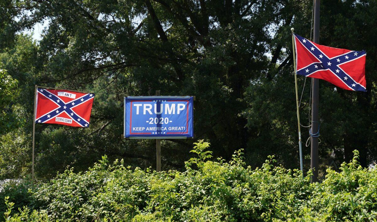 A campaign sign for President Donald Trump sits between two Confederate flags, one bearing the words "I ain't coming down," in the backyard of a home in Sandston, Va., on July 4, 2020. (Kevin Lamarque/Reuters)